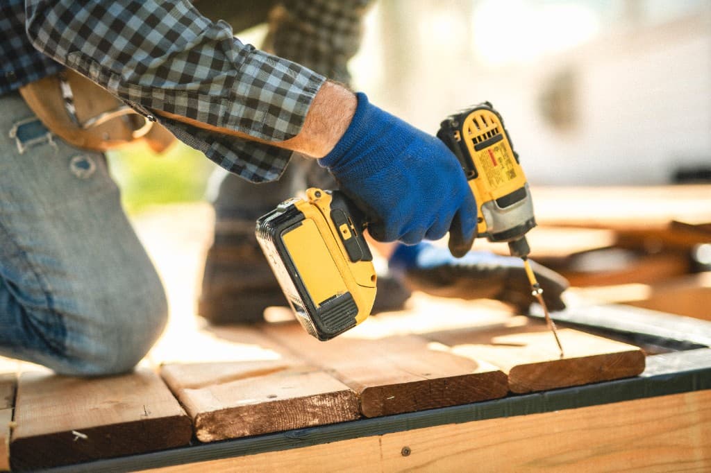 Contractor fastening deck boards with a cordless drill on a sunny afternoon