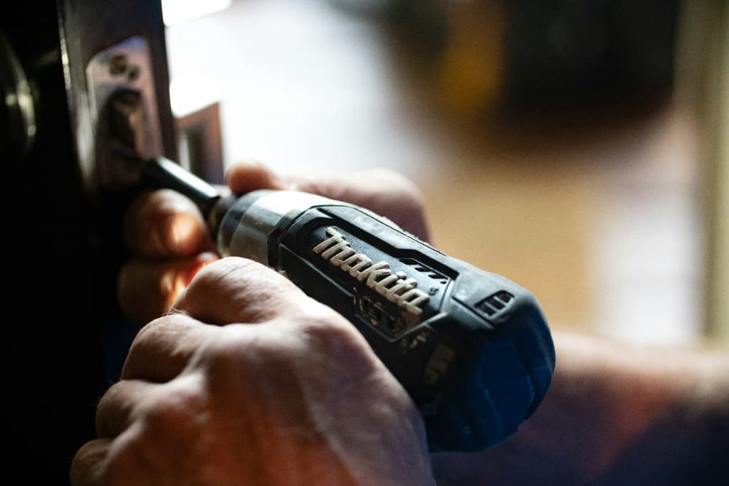 Close-up of a contractor driving a screw into a door frame with a compact drill
